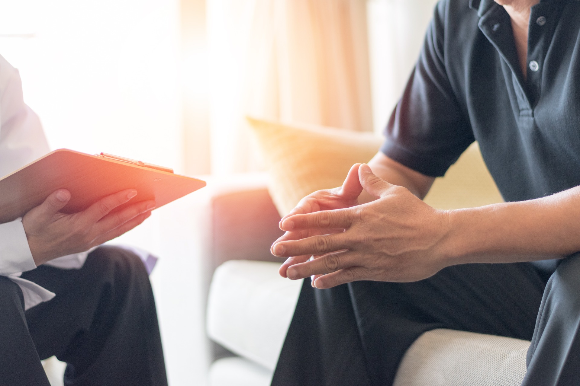 Zwei Personen sitzen sich gegenüber, eine hält ein Tablet, die andere reicht die Hand zur Unterstützung.
